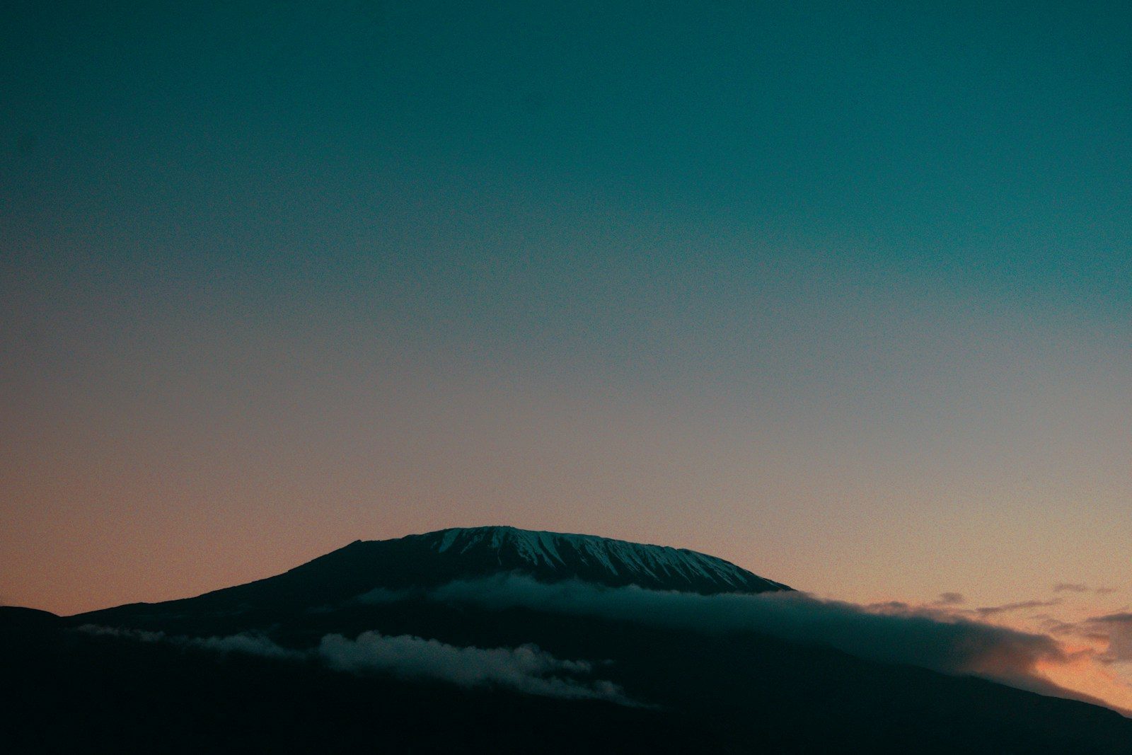 a mountain covered in clouds at sunset